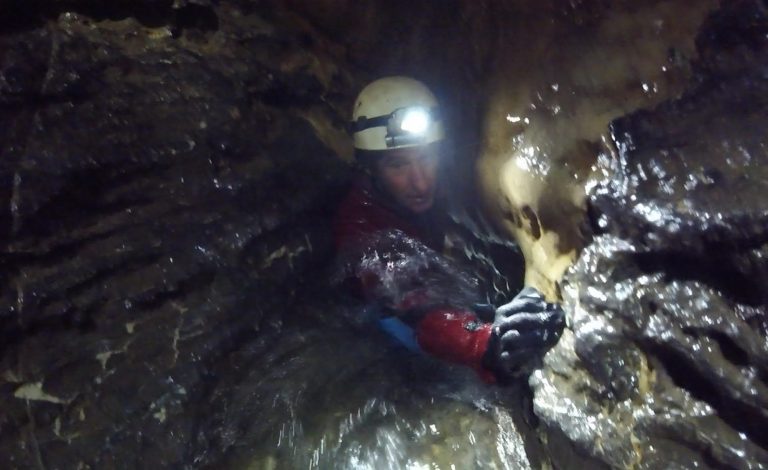 Neil emerging from the lavatory pan in Swildon’s Hole Adventure Caving, Swildon's Hole, the Mendips